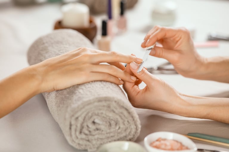 Woman receiving manicure by beautician with metal nail file