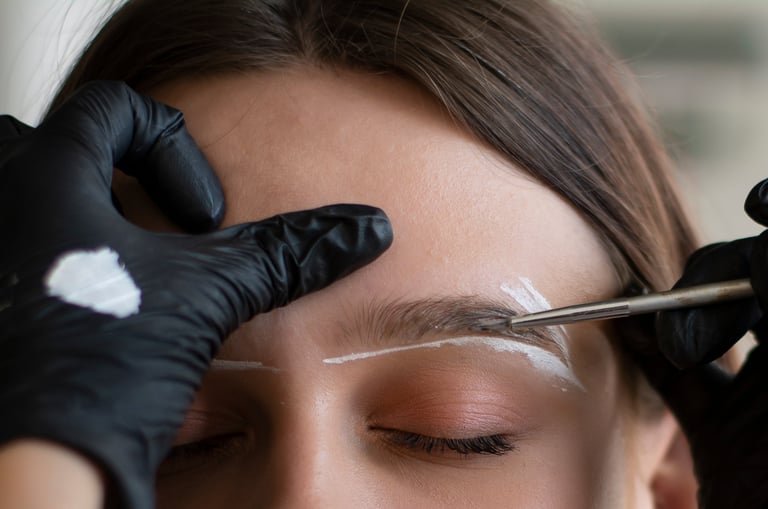 Young woman undergoing eyebrow correction procedure in beauty salon