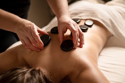 Hot stone massage therapy on back during spa treatment