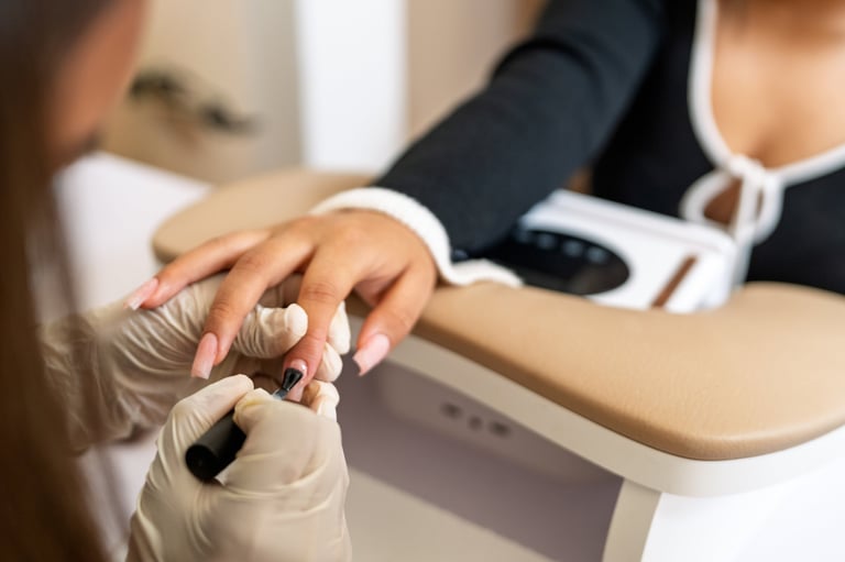 Manicurist applying nail polish to a client's hand with new color